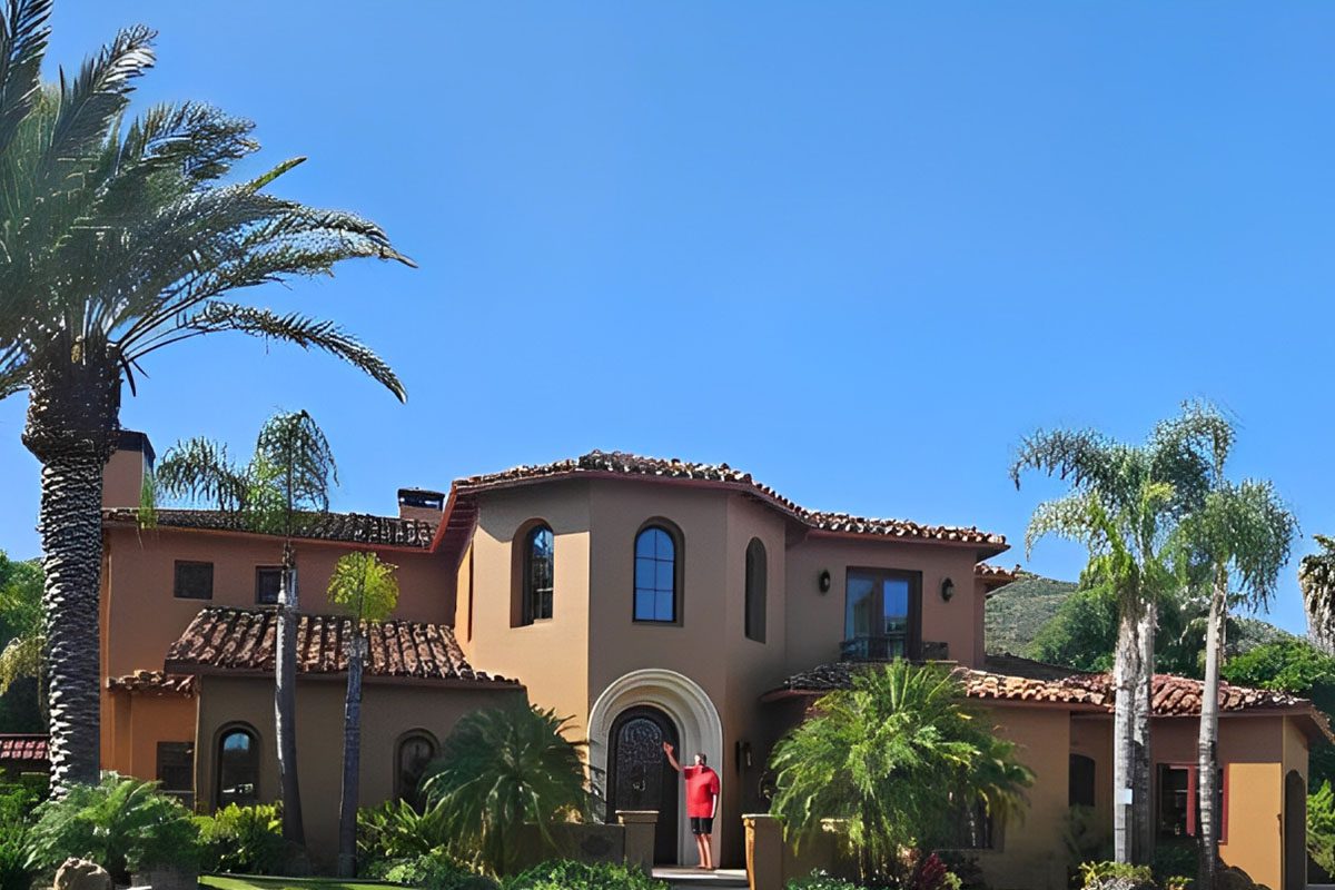 A person standing in front of a large house.