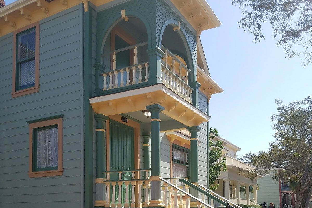 A green house with two balconies and a balcony railing.