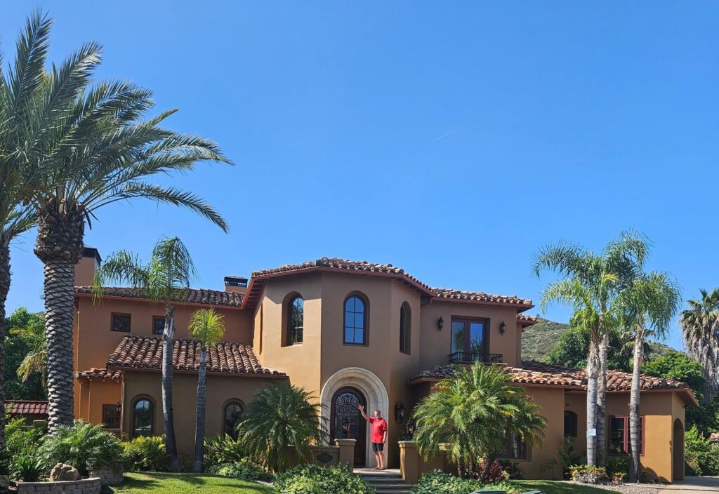 A large brown house with palm trees in front of it.