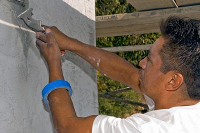 A man is painting the side of a house.