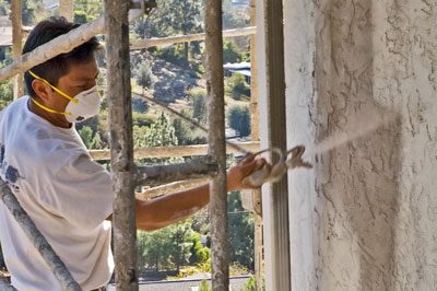 A man spraying paint on the outside of a building.